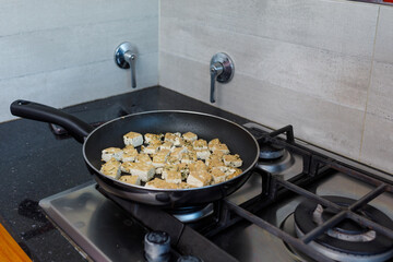 Tofu browning in the pan over the stove fire. Soy cheese for cooking vegetarian or vegan foods. Healthy, nutritious and protein food. Care for the environment and ecosystem. Animal protection.