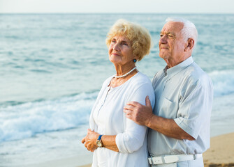 portrait of old happy pensioners standing together on the beach