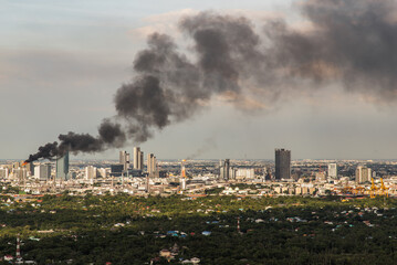 Bangkok, Thailand - 10 Oct, 2021 : Plume of smoke clouds from Burnt industrial or office building on fire at some area in the city. Fire disaster accident, Selective focus.