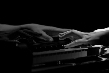 black and white of woman hands playing on a piano