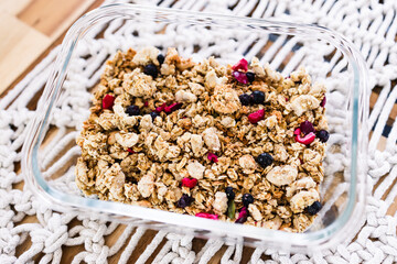 vegan homemade granola with oats grains and dried fruits in glass lunch box, healthy plant-based food