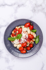 Gnocchi with tomatoes, red sauce, cheese and basil leaves