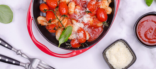 Gnocchi with tomatoes, red sauce, cheese and basil leaves