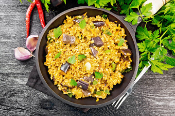 Bulgur with eggplant in pan on board top