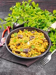 Bulgur with eggplant in pan on wooden board
