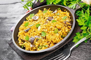 Bulgur with eggplant in pan on wooden table