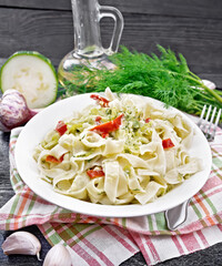 Fettuccine with zucchini and hot peppers in plate on black board
