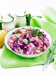 Salad with herring and beetroot in bowl on napkin