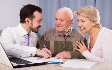 Aged couple signing financial agreement with social worker at home