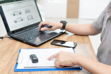 A man check data on check sheet document and use laptop computer in put data with car service in car service center