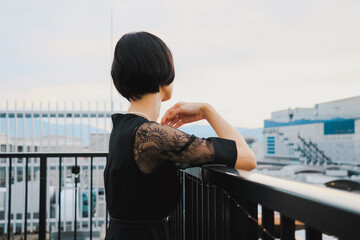 ドレスを着たショートヘアの女性モデルが街を眺める