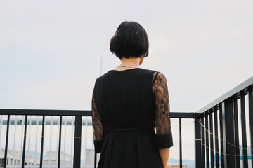 黒いドレスを着たショートヘアの女性モデルが空を眺める