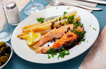 Traditional spanish food, grilled salmon with asparagus served with lemon and greens