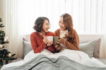 Obraz na płótnie Canvas friendship concept - two beautiful women drinking coffee or tea at home