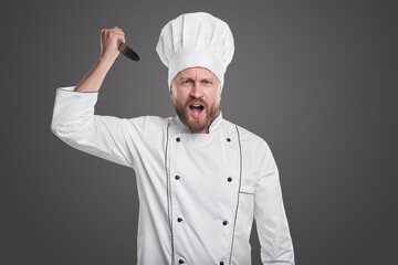 Angry chef with knife on gray background