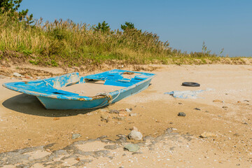 Fototapeta na wymiar Damaged flat bottom boat filled with sand abandoned on beach.