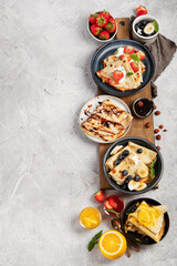 Sweet crepes assortment with berries chocolate on gray background.