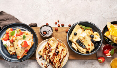 Sweet crepes assortment with berries chocolate on gray background.