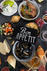French dishes and appetizers served on dark background.
