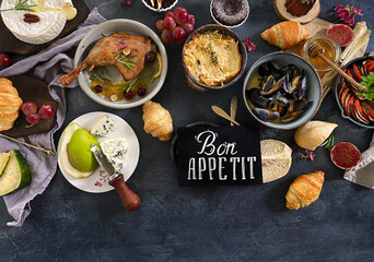 French dishes and appetizers served on dark background.