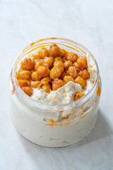 Take Away Hummus with Crispy Chickpeasi Olive Oil, Paprika and Lemon in Glass Bowl.