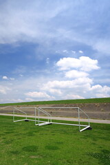 初夏のゴールポストのある江戸川河川敷のサッカー場と護岸のある土手風景