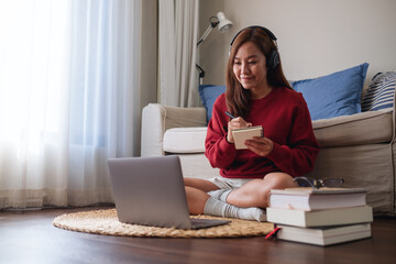 A young woman with headphone using laptop computer for online study at home