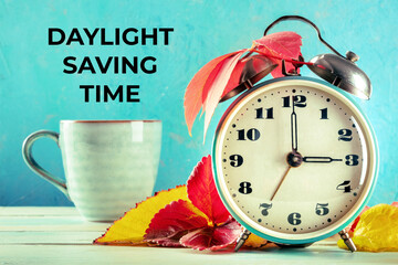 Daylight Saving Time concept, fall back in autumn. A vintage alarm clock with a mug of coffee and...