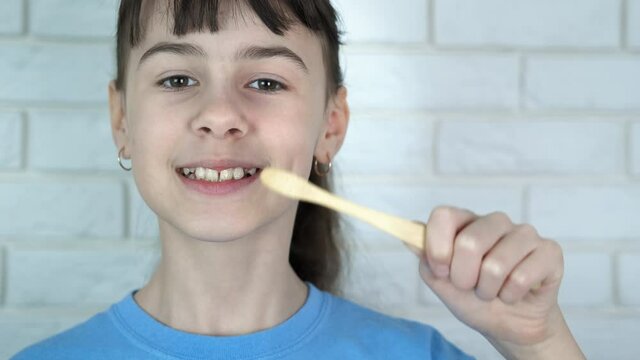 Teenager with eco toothbrush. A cute teenage girl shows a natural bamboo toothbrush.