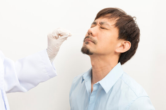 Covid Diagnostic Procedure. Doctor Making Nasal PCR Test For Adult Asian Man, Using Sterile Swab Stick, Coronavirus COVID-19 ATK Diagnostic.