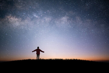 Young traveler and backpacker standing and raise both arms watched the star and milky way alone on...