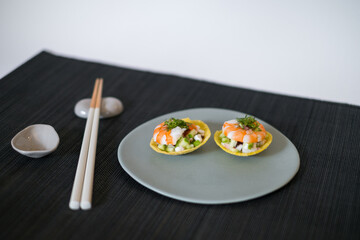 Asian style shrimp tartlets on grey plate with wooden chopsticks on black background in Japanese restaurant. Top view, close up, photo for the menu