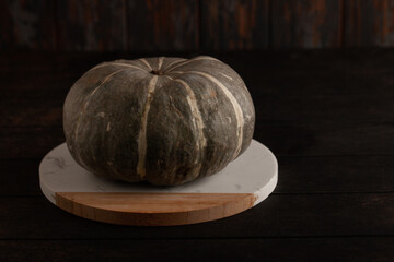 Green pumpkin on rustic wooden table with copy space. Thanksgiving decoration. Trendy organic...