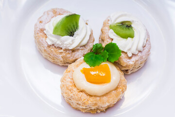 cream cakes and tropical fruits on the white plate