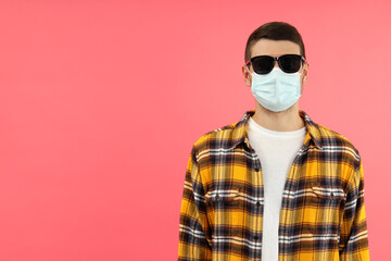 Young man in sunglasses and mask on pink background, space for text