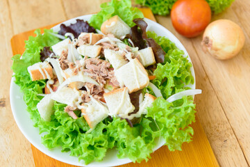 Closeup to tuna salad in the white dish on wood plate