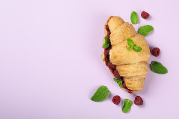 Croissant with raspberry jam on purple ​background