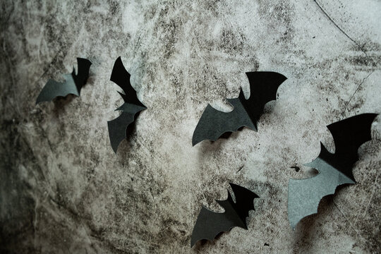 Paper bats flying against a stone wall background
