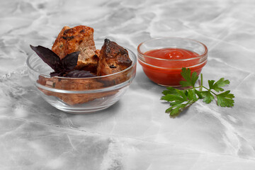 Grilled pork in a bowl with sauce and greens.