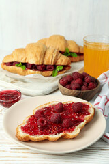 Concept of delicious food with croissants with raspberry jam on white wooden background