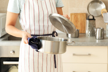 Woman in apron holds metal pot, space for text