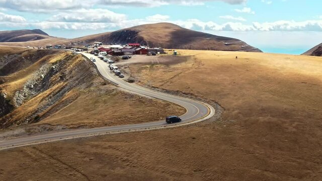 Aerial drone view of nature in Romania. Carpathian mountains, sparse vegetation, Transalpina road with camp and moving cars
