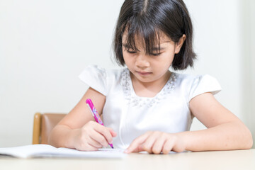 Cheerful Asian little girl children student writing on notebook doing homework and self study at home. Education Homeschool Concept Stock Photo