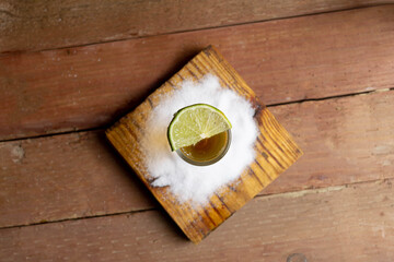 Fototapeta na wymiar top view shot of golden tequila with lemon and salt on planks