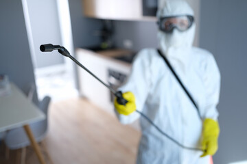 Person in protective suit and mask disinfects kitchen