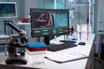 Empty science laboratory with professional tools for research and biochemistry. Nobody in scientific cabinet for development with computer, microscope and vacutainers on desk.