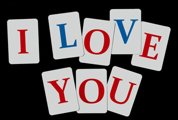 Words I love you composed of letters of blue and red color on white cards laid out on a black background