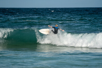 male surfer doing a turn on a wave at the beach in summer on a sunny day