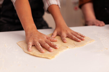 Closeup of granddaughter hands preparing homemade gingerbread making cookies dough celebrating christmas holiday. Child cooking delicious xmas dessert enjoying winter season in x-mas decorated kitchen