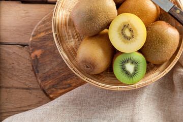 Top view ripe golden kiwi fruit and green kiwi fruit in wood basket on wooden table background....